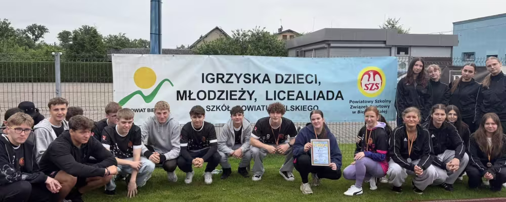 Uczniowie Liceum w Kozach kucają przed banerem