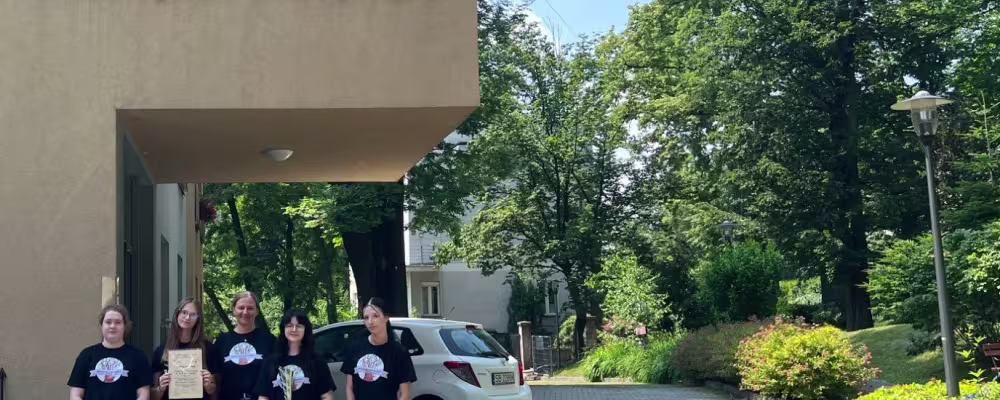 Fotografia: Pięć os&oacute;b przed hospicjum im. św. Jana Pawła II; jedna trzyma certyfikat.